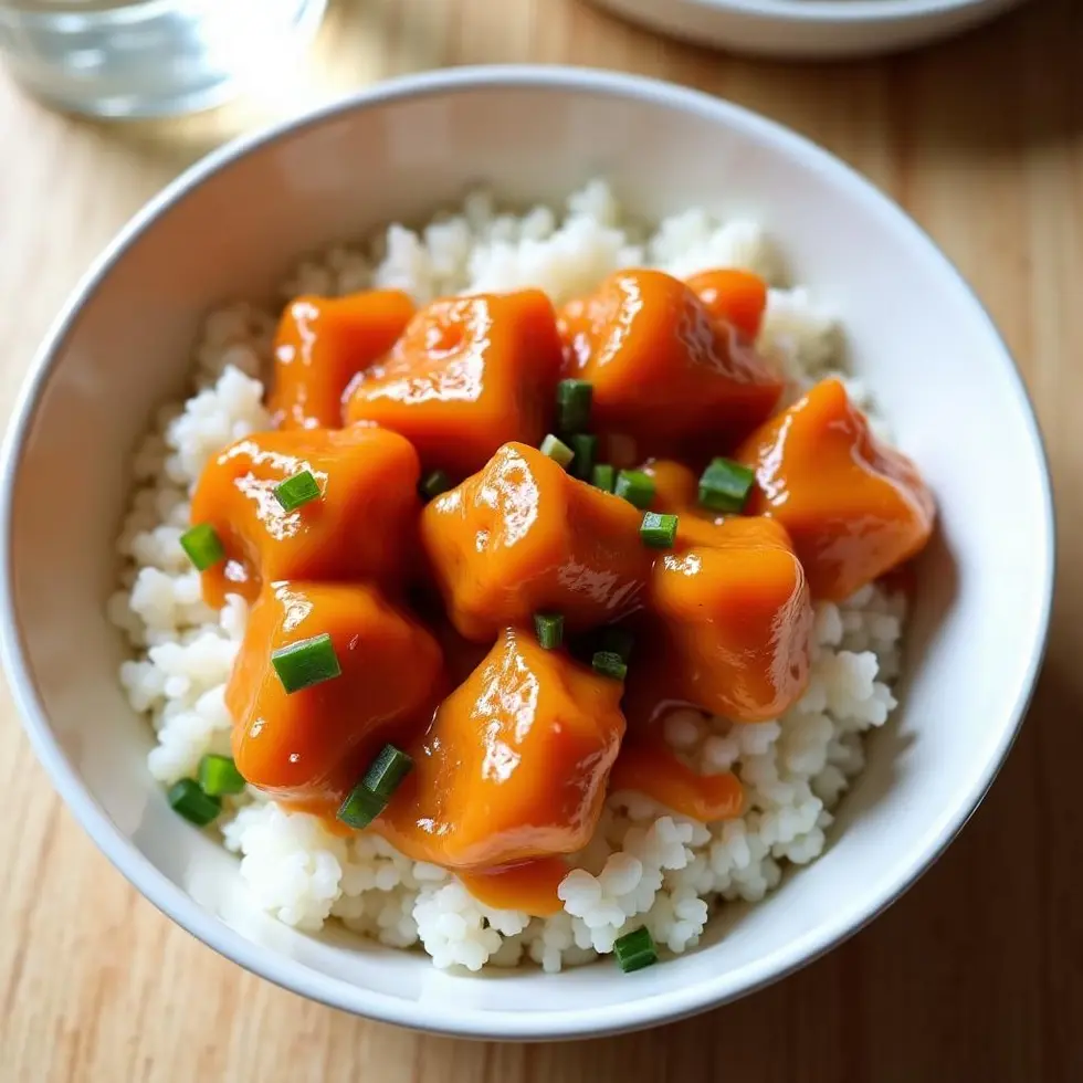 Orange chicken served over steamed white rice in a shallow bowl
