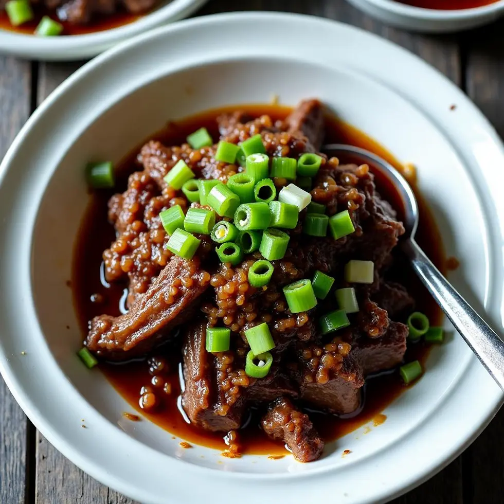 Close-up of tender beef slices coated in thick sauce with green onion pieces
